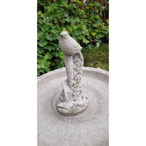 Tree trunk bird bath with bird on shovel