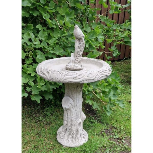 Tree trunk bird bath with bird on shovel