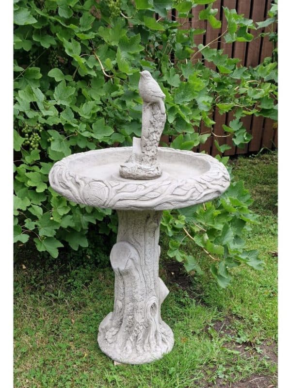 Tree trunk bird bath with bird on shovel